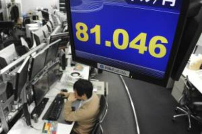 Un empleado trabaja de bajo una pantalla que muestra la evolución del dólar frente al yen en Tokio. EFE/Archivo