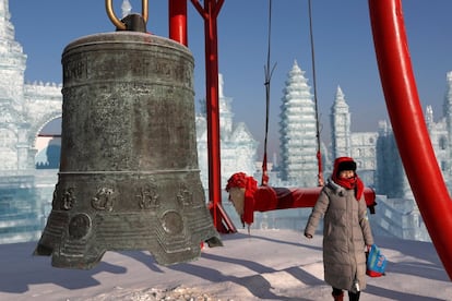 Um visitante posa para uma fotografia em frente a uma das instalações do festival anual de gelo em Harbin.