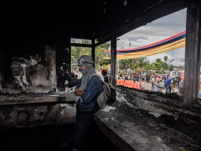 Jovem monta guarda dentro de uma delegacia de polícia que foi incendiada por manifestantes em Puerto Resistencia, Cali, nesta quarta-feira.