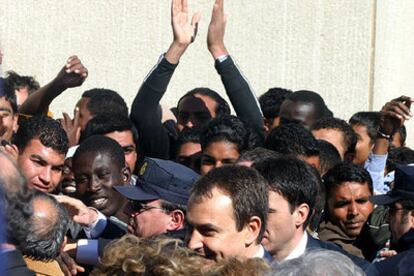 Zapatero, rodeado de inmigrantes durante su visita al CETI. Los internos le han saludado con aplausos y al grito de "papeles y residencia, por favor".