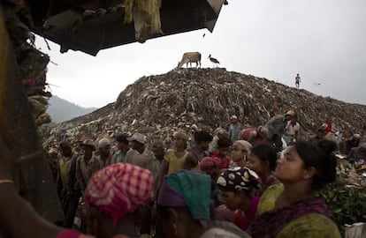 Chatarreros esperan para recoger materiales reciclables mientras un camión se prepara para descargar en un basurero en las afueras de Gauhati, en el estado de Assam.