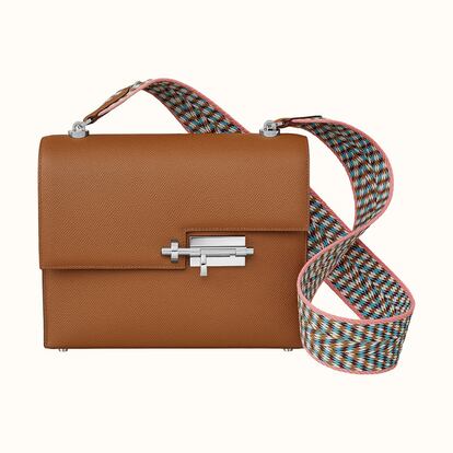 Un dibujo sutil colgado al hombro. El bolso Verrou 21 Strap de Hermès presenta piel de ternera, cierre plateado paladiado en forma de cerrojo, bolsillo de parche y bandolera en cincha Wooly. La piel es de ternera de Epsom, una ciudad célebre por su carreras hípicas, y destaca una flor fina y regular obtenida por grabado mecánico para subrayar un doble tono muy marcado. Al tacto el bolso permanece seco, redondo y firme. Con el paso del tiempo conserva la forma y resiste las rayaduras, aunque se puede atenuar la flor. Precio: 6.050 euros.