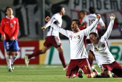 Venezuelan players raise their arms in celebration as their Chilean rivals look on in despair.