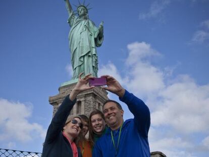 Turistas se fotografían con la estatua de la Libertad tras su reapertura.
