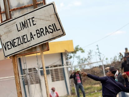 Jovem atira pedra contra policiais da Guarda Nacional venezuelana, em setembro de 2019, na fronteira de Brasil e Venezuela.