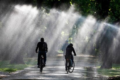 Varias personas se refrescan mientras circulan en sus bicicletas por el parque Tiergarten de Berlín (Alemania).