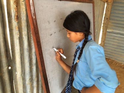 Una niña escribe en la pizarra de un aula temporal en Jhulosiruwari, una remota zona rural de Sindhupalchowk. Las organizaciones humanitarias alertan de que los menores que no atienden a la escuela están en más riesgo de ser explotados o caer en manos de traficantes. Las niñas en el distrito de Sindhupalchow son especialmente vulnerables.