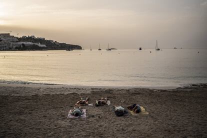 Cinco hombres duermen sobre las toallas al amanecer en la playa Figueretes, Ibiza.