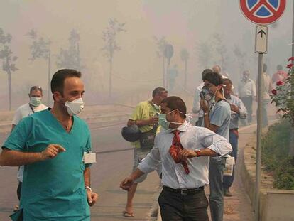 Decenas de personas se protegen del humo con mascarillas al ser evacuadas de un hospital de Cefalú.