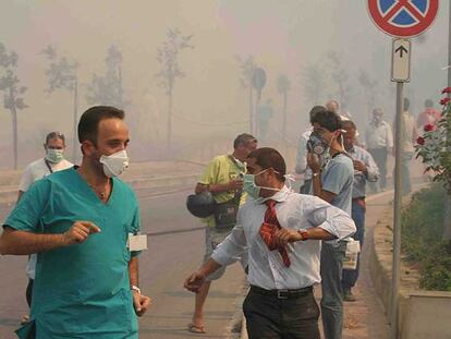 Decenas de personas se protegen del humo con mascarillas al ser evacuadas de un hospital  de Cefalú.