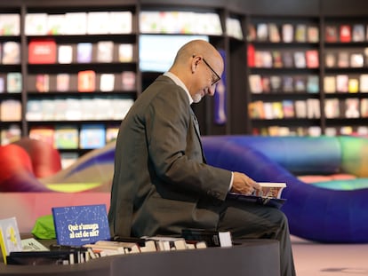 Un visitante de la Feria del Libro lee en el pabellón de España ante un libro escrito en catalán.