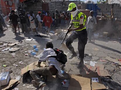 Un policía haitiano apunta a una de las personas presentes en las zonas saqueadas.