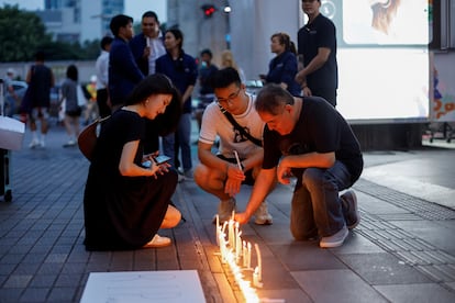 Tourists look at candles placed outside the luxury Siam Paragon shopping mall where police arrested a teenage gunman who is suspected of killing foreigners in a shooting, in Bangkok, October 4, 2023.
