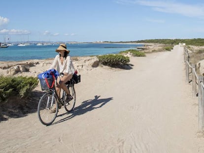 Una mujer circula en bicicleta por la isla balear de Formentera.