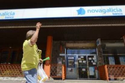 Una afectada por las participaciones preferentes y subordinadas de Novagalicia Banco pasa ante una sucursal de la entidad. EFE/Archivo
