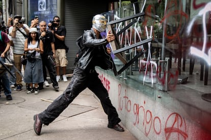 Un manifestante rompe el cristal de una cafetería durante la marcha.