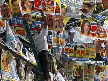 Un trabajador descuelga los carteles electorales en Ciudad Quezón tras los comicios en Filipinas.