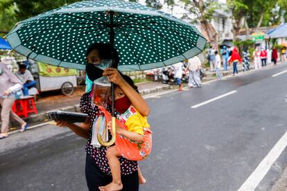 Una mujer con un niño lleva una bandeja de comida para romper el ayuno durante el Ramadán en Yakarta la semana pasada.