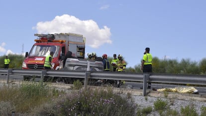 Los bomberos rescatan a una de las víctimas mientras un fallecido permanece sobre el asfalto.