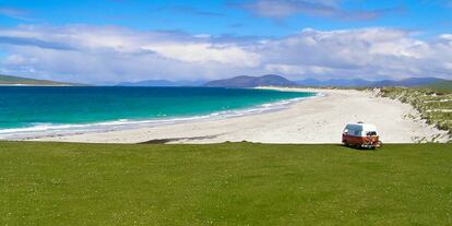 Una furgoneta camper frente a una playa de la isla de Bernerary, en Escocia.