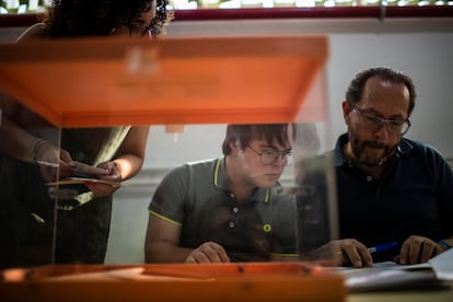 Bruno Ruiz, de 21 años, junto a su padre Juan, en la mesa electoral donde le ha tocado ser segundo vocal, en las elecciones generales del 23 de julio.

