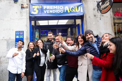 Los ganadores de un tercer premio de la Lotería de Navidad en 2019 brindan con champán en una administración de la calle Arenal de Madrid.