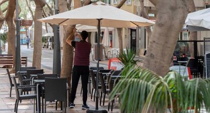 Un camarero coloca una sombrilla en la terraza de un bar en Santa Cruz de Tenerife.