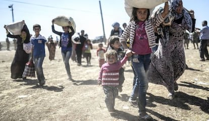 Refugiados sirios huyen de la guerra a través de la frontera con Turquía.  