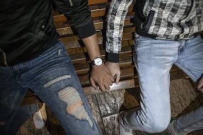 Youssef and Ahmed hand in hand on a bench in the center of Marrakesh.