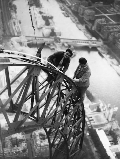 Dos operarios ponen bombillas en la estructura de la Torre Eiffel durante el cambio de la iluminación de 1937. En los 80 se instaló un sistema con proyectores de sodio y, en los 2.000 otro compuesto por flashes.