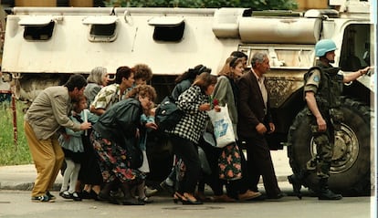 Ciudadanos de Sarajevo, Bosnia, se protegen de los disparos de francotiradores tras un carro de combate de las fuerzas de la ONU