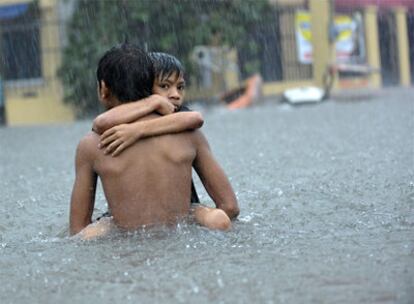 Un niño carga con otro en las afueras de Manila, tras el paso del tifón 'Ketsana'.