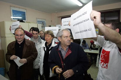 Simpatizantes de EHAK rodean con pancartas a Madrazo (a la izquierda) en su colegio electoral.