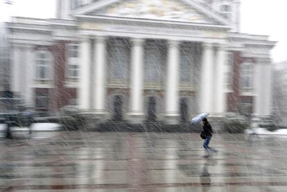 Un mujer corre bajo la nieve frente al Teatro Nacional de Sofía, Bulgaria.