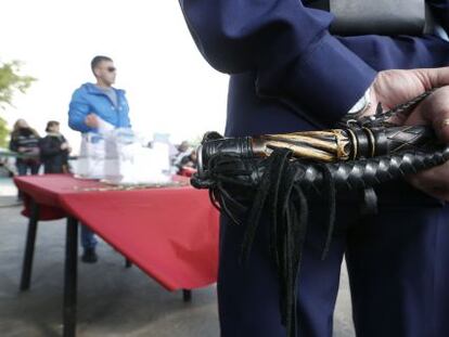 Um cossaco vigia uma urna com um chicote em mãos em uma sede eleitoral para o referendo ucraniano, em Moscou.