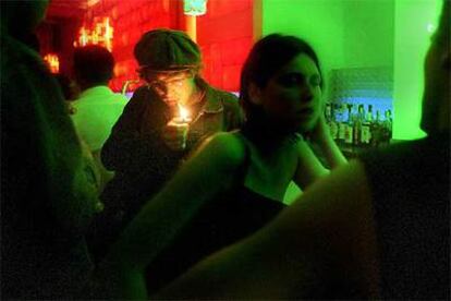 Un cliente enciende un cigarrillo en un bar musical en Barcelona.
