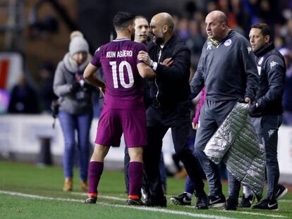 Guardiola sujeta a Ag&uuml;ero ante el entrenador del Wigan Athletic, Paul Cook.