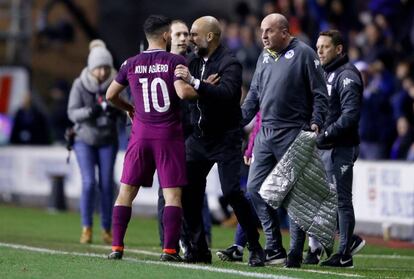 Guardiola sujeta a Agüero ante el entrenador del Wigan Athletic, Paul Cook.