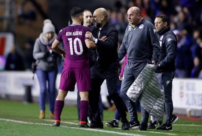 Guardiola sujeta a Ag&uuml;ero ante el entrenador del Wigan Athletic, Paul Cook.