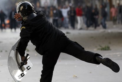 Un policía lanza una piedra hacia los manifestantes durante las protestas en Túnez.