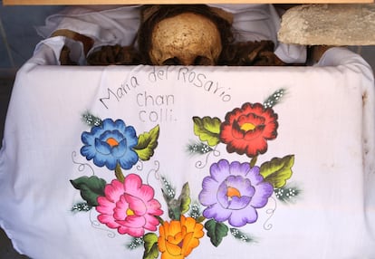 Los restos de una persona fallecida colocados sobre una tela bordada dentro de un osario, después de ser limpiados como parte del ritual anual para honrar a los muertos.