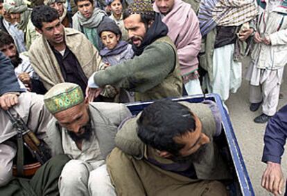 Un combatiente de la Alianza golpea a dos prisioneros talibanes que van camino de la cárcel de la ciudad de Herat.