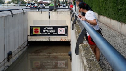 Dos personas observan el nivel alcanzado por el agua, de casi dos metros de altura, en un paso subterráneo este jueves en Zaragoza. 