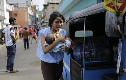 Una vecina de las proximidades del santuario de San Antonio corre con su bebé en brazos mientras la policía trata de desactivar los artefactos explosivos encontrados en un vehículo estacionado en Colombo, este lunes 22 de abril.