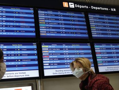 Varias personas con mascarillas pasan frente a un tablón de salidas del aeropuerto París-Orly el martes 17 de marzo. 