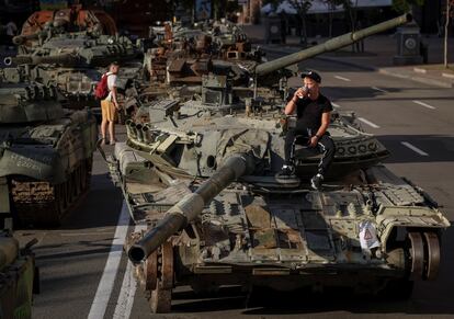 Un hombre bebe un café sobre un tanque ruso destruido expuesto en la calle principal Jreshatik de Kiev, como parte de la celebración del Día de la Independencia de Ucrania, este miércoles.