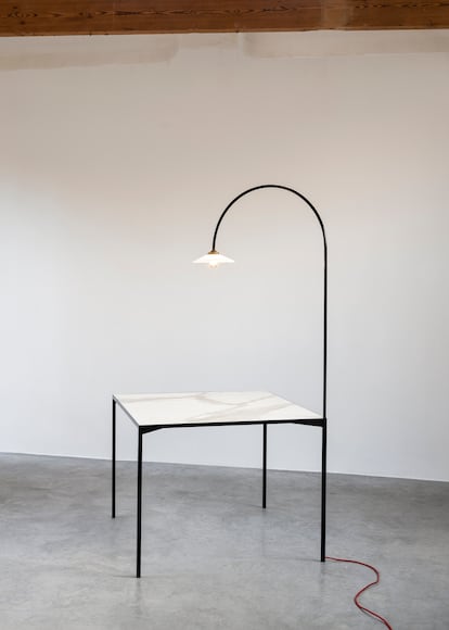 Mesa + lámpara, obra en la que el arco de la lámpara contrasta con las formas rectangulares de la mesa minimalista.