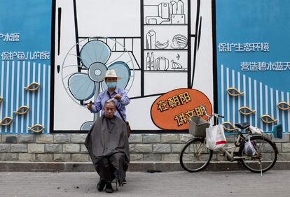 Un peluquero le corta el pelo a un cliente en una calle de Pekín. Pese a algún brote concreto, como el de julio del mayor mercado mayorista de la ciudad, Pekín ha conseguido controlar la incidencia del virus entre su población. En China se registraron este domingo solo 21 casos confirmados en todo el país.