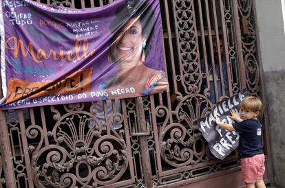 Criança cola cartaz em homenagem à vereadora Marielle Franco.