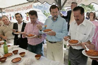 El presidente del Partido Popular, Mariano Rajoy, acompañado por autoridades locales y por el presidente del PP de Galicia, Alberto Núñez (centro), prueba un plato de callos en una caseta de la XIV Fiesta de los Callos, en Salceda de Caselas.